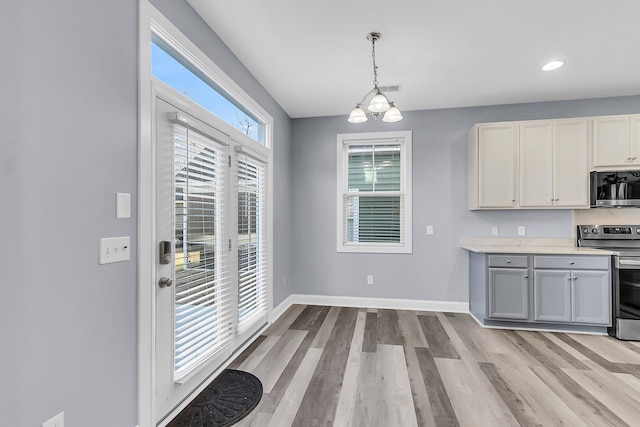 kitchen featuring stainless steel appliances, baseboards, light countertops, and light wood finished floors