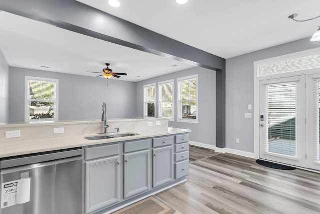 kitchen with baseboards, dishwasher, light wood-style flooring, gray cabinets, and a sink