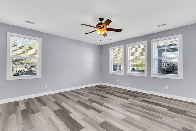 unfurnished room featuring baseboards, visible vents, and a wealth of natural light