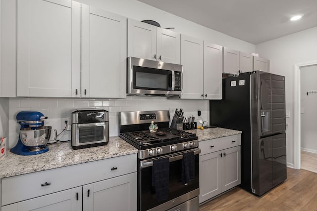 630 Jancus St, Charleston, SC 29414 - kitchen featuring stainless steel appliances, baseboards, decorative backsplash, light wood-style floors, and light stone countertops