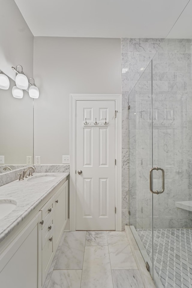 full bath featuring a sink, marble finish floor, a stall shower, and double vanity