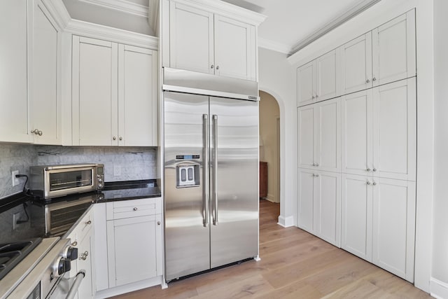 kitchen featuring a toaster, arched walkways, ornamental molding, stainless steel built in fridge, and range