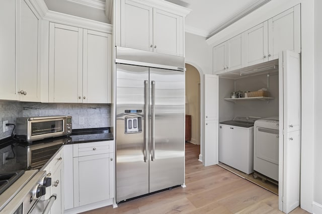 kitchen featuring washing machine and clothes dryer, stove, stainless steel built in refrigerator, ornamental molding, and arched walkways