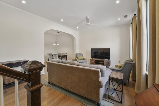 living room with arched walkways, recessed lighting, ceiling fan with notable chandelier, and light wood-style floors