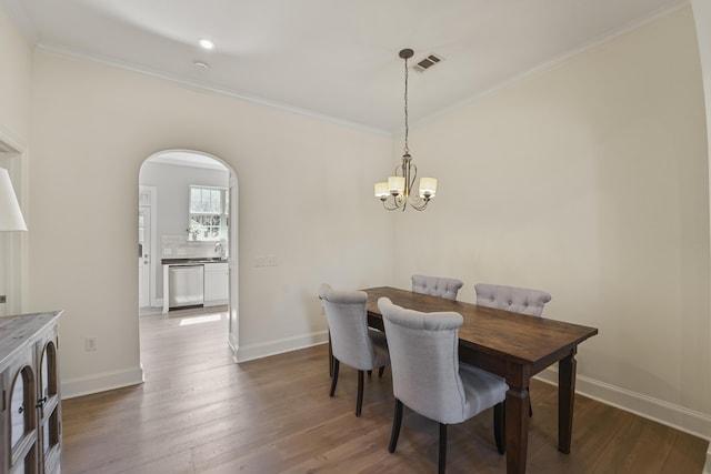 dining area with crown molding, dark wood-type flooring, baseboards, an inviting chandelier, and arched walkways