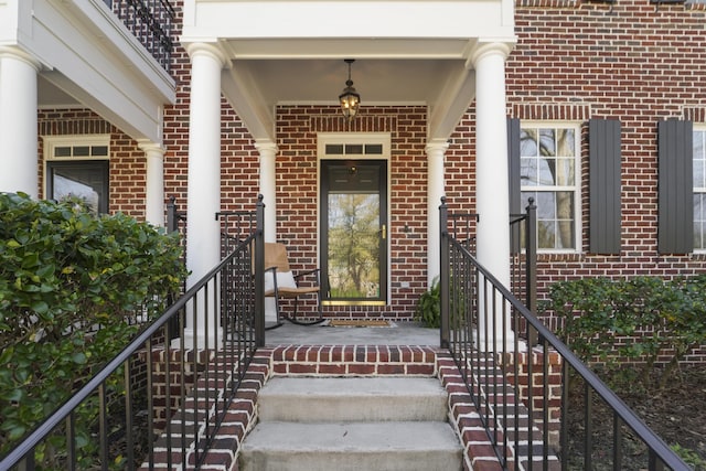 view of exterior entry with brick siding and a porch