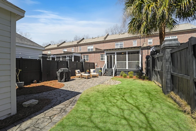 view of yard featuring a patio, entry steps, a fenced backyard, and a sunroom