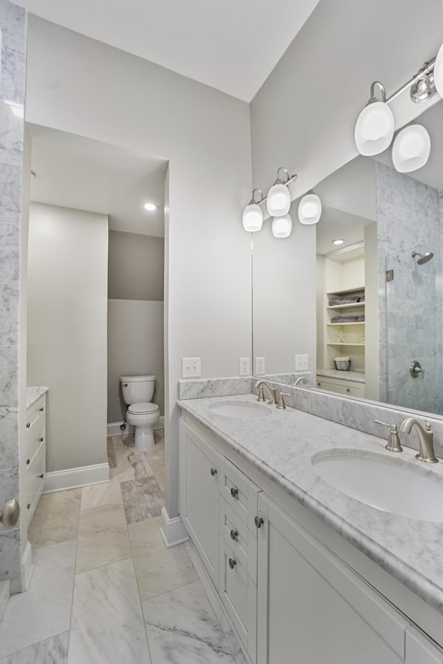 bathroom featuring a tile shower, marble finish floor, double vanity, and a sink