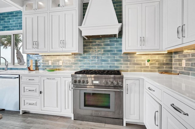 1404 Palmetto Blvd, Edisto Beach, SC 29438 - kitchen featuring tasteful backsplash, light countertops, white cabinets, custom range hood, and appliances with stainless steel finishes
