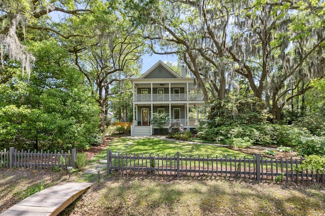 view of front facade featuring a porch, ceiling fan, a fenced front yard, a front yard, and a balcony