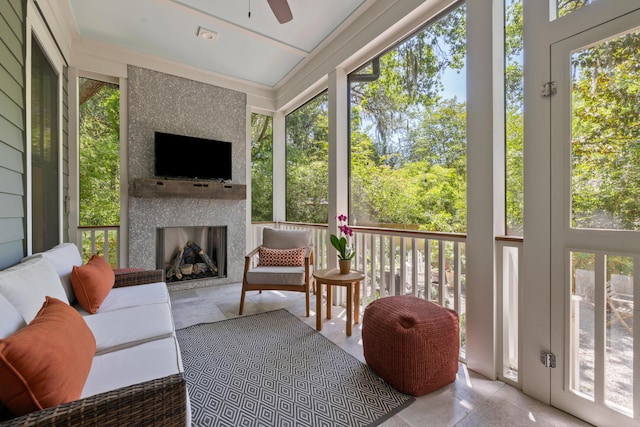 sunroom / solarium featuring a ceiling fan and an outdoor living space with a fireplace