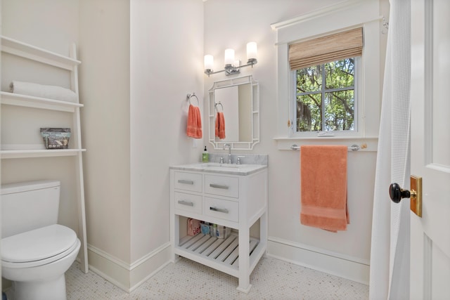 bathroom with baseboards, tile patterned floors, toilet, and vanity