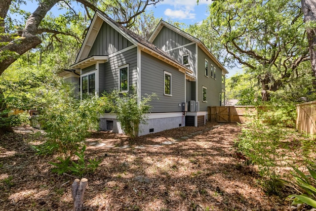 view of side of home with a gate, board and batten siding, fence, and crawl space