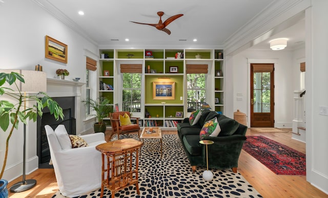 sitting room with crown molding, ceiling fan, wood finished floors, and a fireplace