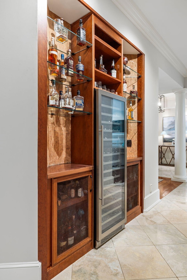 bar with decorative columns, ornamental molding, light tile patterned floors, and wine cooler