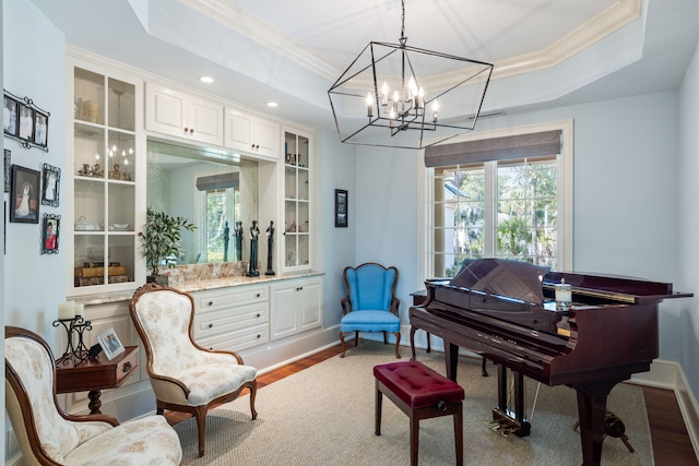 living area with crown molding, wood-type flooring, and a raised ceiling