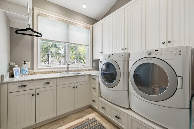 washroom with light tile patterned flooring, cabinets, washer and clothes dryer, and sink