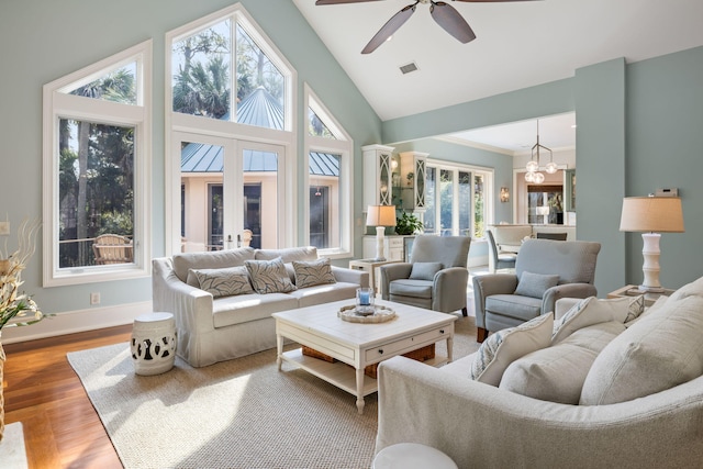 living room with ceiling fan with notable chandelier, high vaulted ceiling, plenty of natural light, and light hardwood / wood-style floors