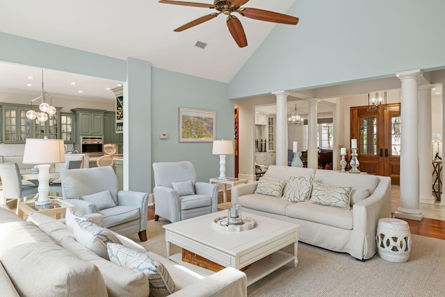 living room with decorative columns, crown molding, high vaulted ceiling, light hardwood / wood-style flooring, and ceiling fan with notable chandelier