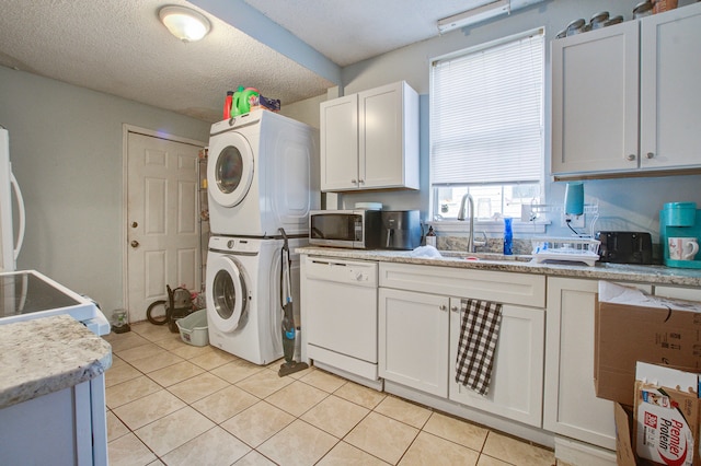 washroom featuring stacked washing maching and dryer, a textured ceiling, sink, and light tile patterned flooring