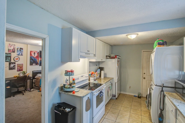 kitchen featuring white appliances, light carpet, stacked washer and dryer, and white cabinets