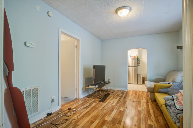 living area featuring light wood-type flooring and a textured ceiling