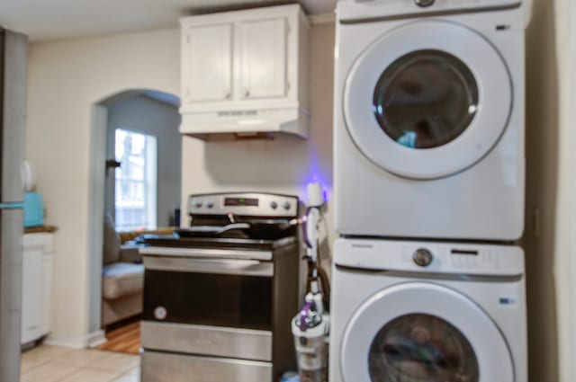 laundry area featuring light tile patterned flooring and stacked washer and dryer