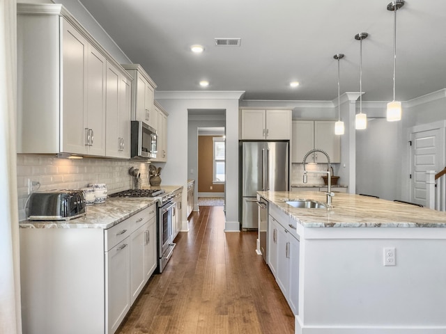 kitchen with ornamental molding, an island with sink, high end appliances, visible vents, and a sink