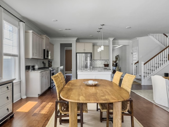 dining area featuring dark wood-type flooring, ornamental molding, visible vents, and stairway