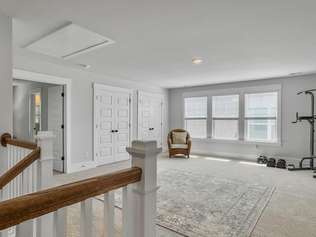living area featuring baseboards, light carpet, an upstairs landing, attic access, and visible vents
