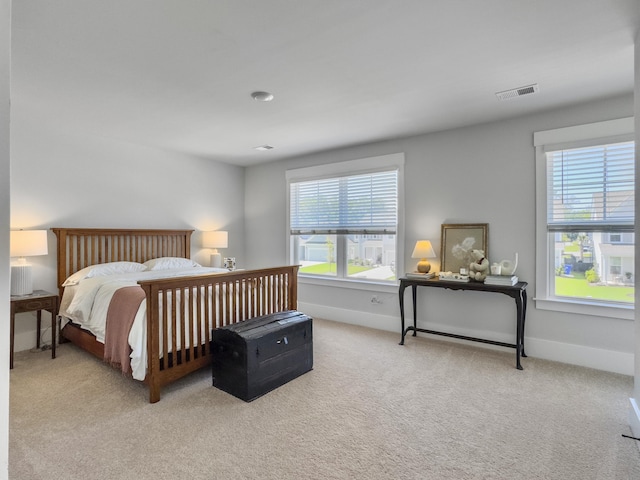 bedroom with light carpet, visible vents, multiple windows, and baseboards