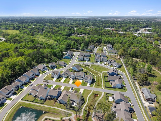 drone / aerial view with a wooded view, a residential view, and a water view
