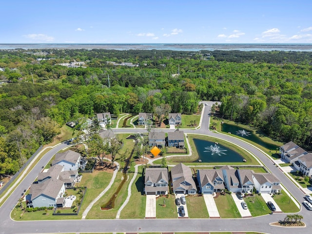 drone / aerial view featuring a forest view, a residential view, and a water view