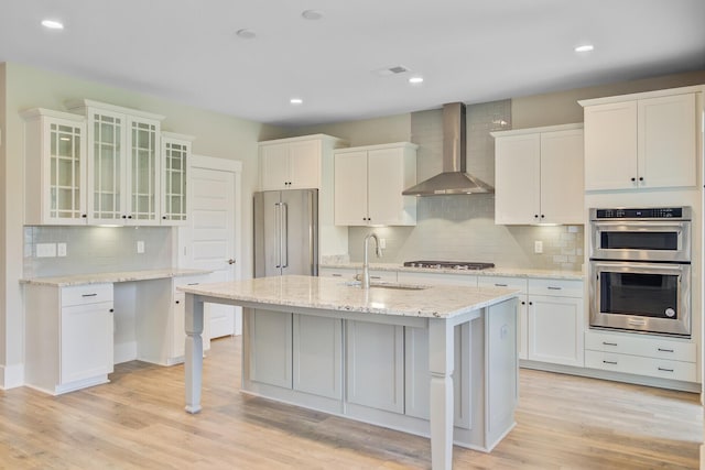 357 Parish Farms Dr, Summerville, SC 29486 - kitchen featuring wall chimney exhaust hood, appliances with stainless steel finishes, decorative backsplash, glass insert cabinets, and light wood finished floors