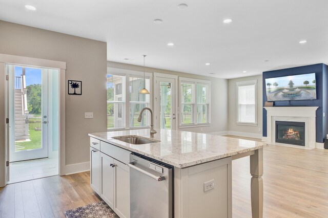 357 Parish Farms Dr, Summerville, SC 29486 - kitchen with dishwasher, light wood-style floors, a glass covered fireplace, light stone countertops, and a kitchen island with sink