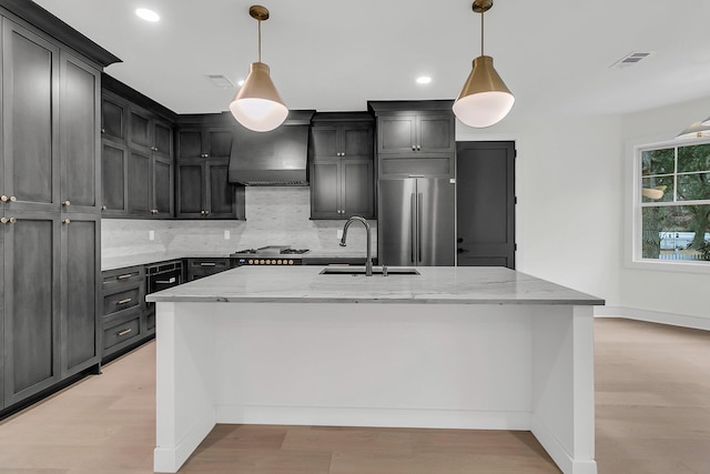 kitchen featuring hanging light fixtures, sink, stainless steel fridge, and a large island with sink