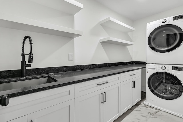 washroom with sink, cabinets, and stacked washer and clothes dryer