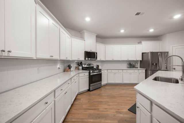 701 Squire Pope Rd, Summerville, SC 29486 - kitchen featuring appliances with stainless steel finishes, white cabinetry, tasteful backsplash, recessed lighting, and light wood-style flooring