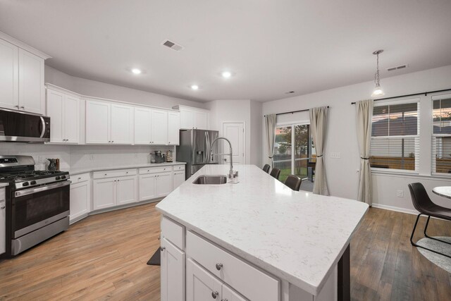 701 Squire Pope Rd, Summerville, SC 29486 - kitchen featuring appliances with stainless steel finishes, light wood-style flooring, an island with sink, recessed lighting, and white cabinetry