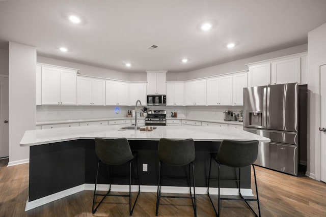 701 Squire Pope Rd, Summerville, SC 29486 - kitchen featuring appliances with stainless steel finishes, a large island with sink, white cabinets, a kitchen bar, and dark wood-style floors