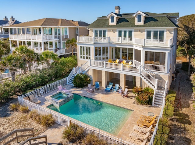 back of property featuring a swimming pool with hot tub, a balcony, and a patio area