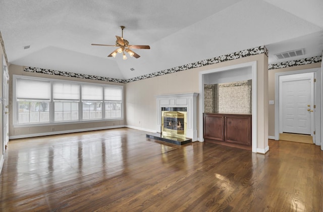 unfurnished living room featuring a wealth of natural light, ceiling fan, dark hardwood / wood-style floors, and vaulted ceiling