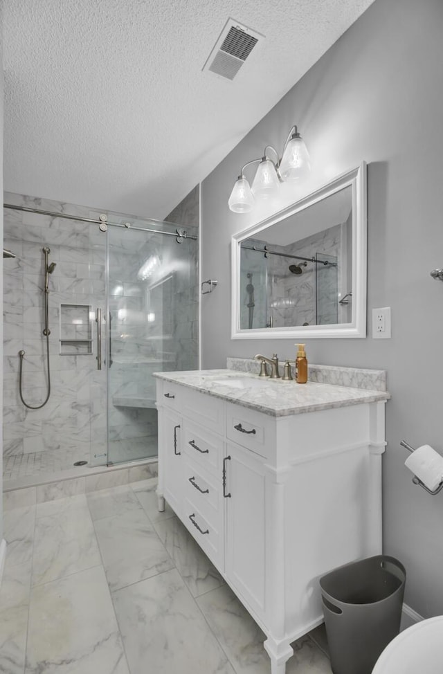 bathroom with vanity, an enclosed shower, and a textured ceiling