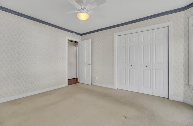 unfurnished bedroom featuring ceiling fan, a closet, light colored carpet, and ornamental molding