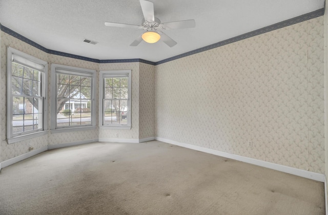 unfurnished room featuring carpet, a textured ceiling, ceiling fan, and crown molding