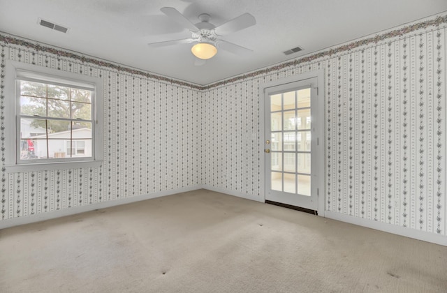 carpeted empty room featuring ceiling fan and a wealth of natural light