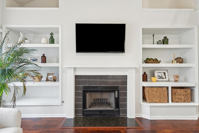 living room with a tiled fireplace and dark hardwood / wood-style floors