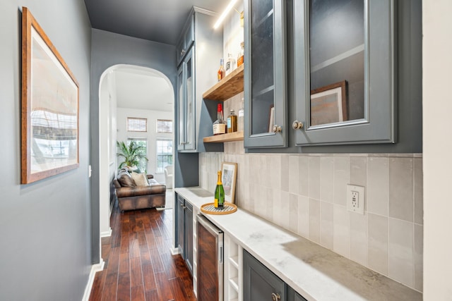 bar with backsplash, dark wood-type flooring, beverage cooler, and gray cabinets