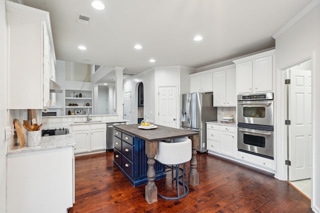 kitchen featuring sink, stainless steel appliances, a center island, white cabinets, and wood counters