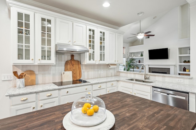 kitchen with sink, dishwasher, light stone counters, white cabinets, and vaulted ceiling